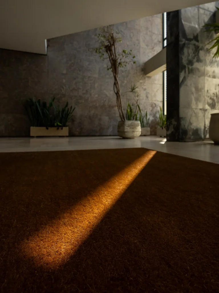 Smuga ciepłego światła wpada przez okno do portierni apartamentowca z lat siedemdziesiątych.