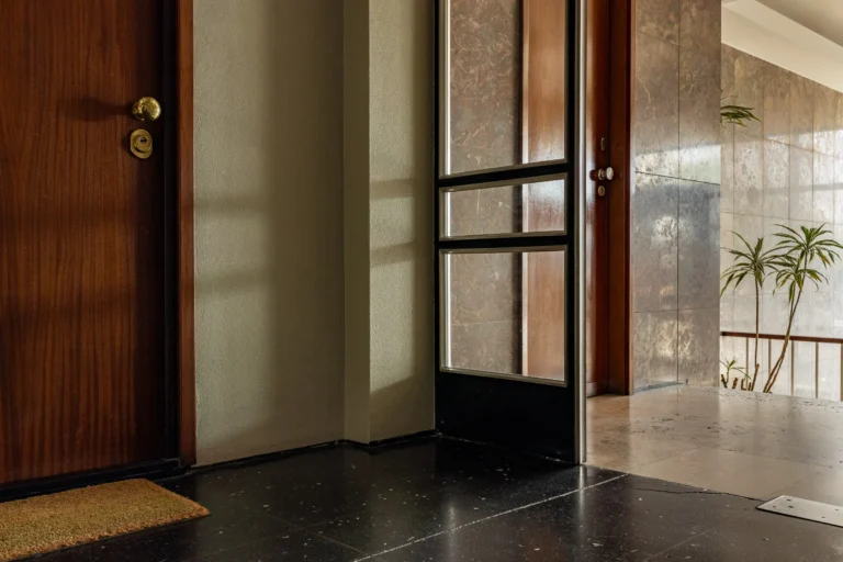 Korytarz budynku mieszkalnego z lat siedemdziesiątych oświetlony słońcem.