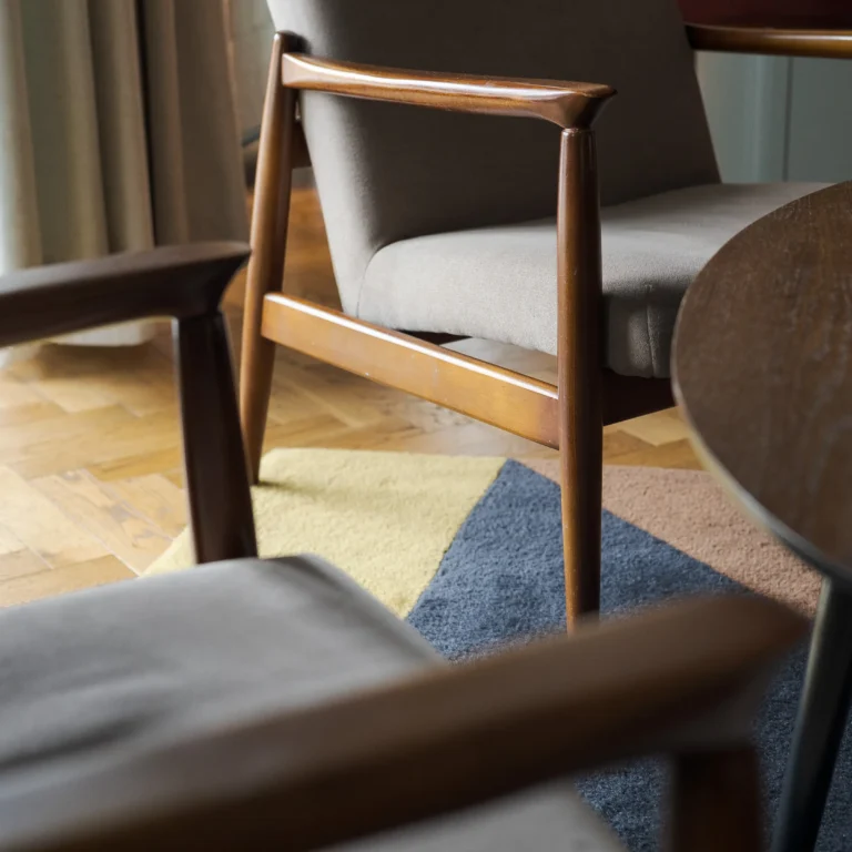 Modernistyczne fotele na kolorowym dywanie w świetle dnia.