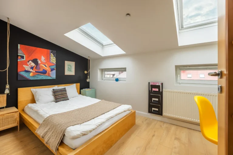 Sypialnia z podwójnym łóżkiem i oknami dachowymi w mieszkaniu w Kielcach.
