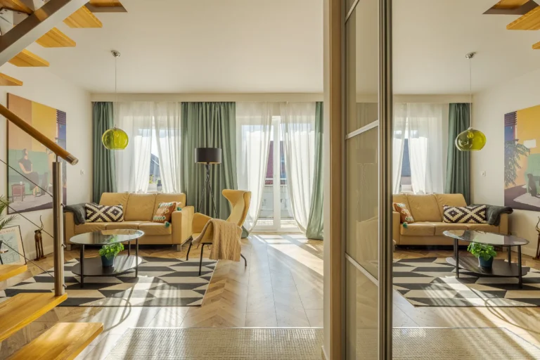 Słoneczny salon ze schodami i odbicie w dużym lustrze.