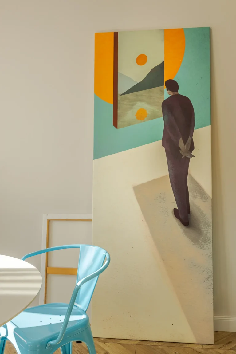 Duży nowoczesny obraz i niebieskie krzesło przy okrągłym stole.