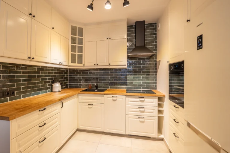 Kuchnia z jasnymi szafkami i drewnianym blatem w mieszkaniu w Warszawie.